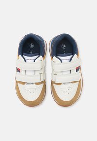Witte en bruine kindersneakers met klittebands, met een blauwe stoffen voering en kleurrijke accenten, loopzool met grippatroon. Maat 24.