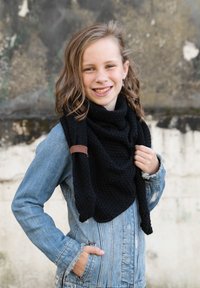 Czarny, dziany szalik o teksturowanym wzorze, noszony na jasnoniebieskiej kurtce dżinsowej. Szalik ma brązowy skórzany detal z metką.