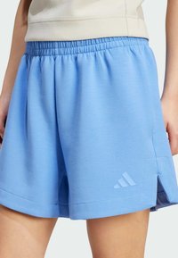 Modré sportovní šortky s elastickým pasem, bočními rozparky a jemně embosovaným logem. Vyrobeny z měkkého materiálu, vhodné pro aktivní nošení.