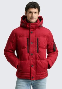 Jachetă puffer roșie cu glugă cu fermoar, multiple buzunare negre cu fermoar și cusături vizibile. Are un sistem de închidere cu nasturi și o țesătură texturată.