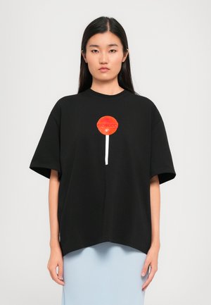 Black oversized t-shirt featuring a red lollipop graphic with white accents. Made from cotton with a soft texture and a relaxed fit.
