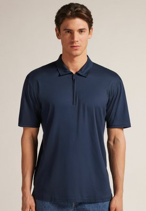 Navyblauwe polo met een korte rits, gemaakt van een gladde stof. Heeft een klassieke kraag en korte mouwen met een relaxte pasvorm.