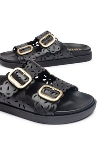 Sandalias negras con patrón floral recortado, dos hebillas doradas ajustables y una plantilla con textura. Suela gruesa para mayor comodidad y soporte.