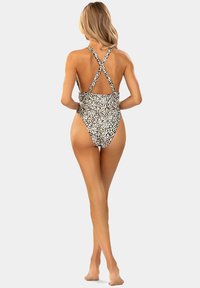 Kostium kąpielowy w czarno-białą panterkę z krzyżującymi się ramiączkami z tyłu, wysokimi wycięciami na nogi i dopasowanym krojem.