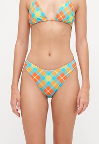 Driehoekige bikini in een meerkleurig ruitpatroon met oranje, blauw en gele tinten. Materiaal lijkt textuur te hebben met dunne banden.