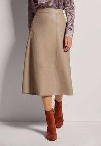 Beige leren A-lijn midi rok met gestikte paneeldetails, gecombineerd met bruine suède enkellaarsjes met een zijrits.