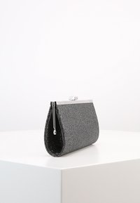 Clutch nera glitter con hardware argento, forma arrotondata e chiusura a scatto. Texture liscia con superficie luccicante.