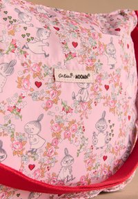Roza tkaninska torba s cvetličnimi vzorci in pravljičnimi liki Moominov. Rdeč trak in etiketa na strani. Gladek otip s igrivim dizajnom.