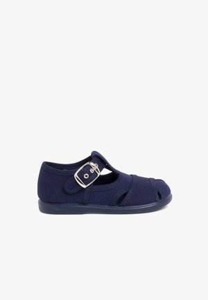 Navy blue canvas shoe with cutouts and a side buckle closure. Features a flexible rubber sole and reinforced stitching for durability.