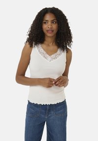 White ribbed tank top featuring a lace-trimmed V-neckline and scalloped hem, paired with high-waisted blue denim jeans.