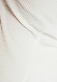 Lichtbeige ribbelstof met een subtiele glans, met een vloeiende val en gladde textuur, die fijne lijnpatronen door het geheel benadrukt.