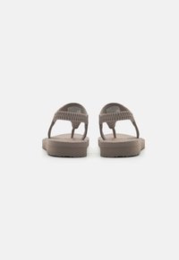 Ruske rubber flip-flop sandaalit, joissa on punottuja hihnoja, tasainen pohja ja teksturoitu pohja hienovaraisella brändityksellä.