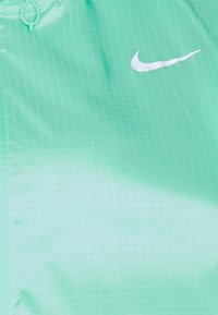 Lichtgroene getextureerde stof met witte rasterlijnen en een wit Nike swoosh-logo dicht bij de rechterbovenhoek.