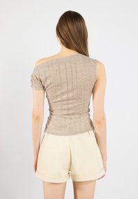 Beige, lättviktig top med en axel, i texturerad tyg med subtila ränder. Kombination med ljusfärgade, skräddarsydda shorts.