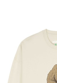 Beige sweatshirt met een gedetailleerde afbeelding van een bruine beer, gedeeltelijk zichtbaar aan de rechterkant van de voorkant.