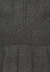 Grijs gebreide jurk met een gestructureerd visgraatpatroon, een geribde tailleband en een gelaagde geplooide rokgedeelte. Zachte, comfortabele stof.