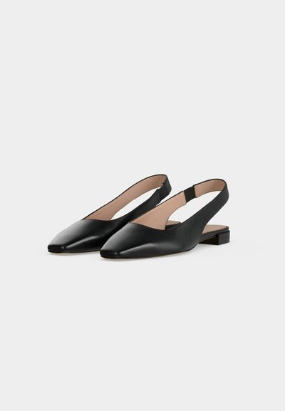 Ζεύγος μαύρα δερμάτινα slingback χαμηλά παπούτσια με μυτερά μύτα και χαμηλά τακούνια, εμφανίζονται σε ανοιχτό γκρι φόντο.