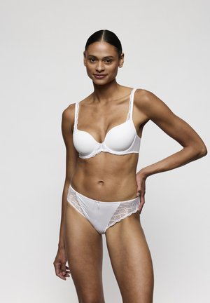 Witte beha met kanten afwerking, gevormde cups en verstelbare bandjes, gecombineerd met bijpassende doorschijnende witte slip met kantaccenten, met een gladde textuur.