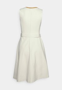 Bezramenné šaty ve tvaru A v krémové barvě, s kulatým výstřihem, zadním zipem a páskem z látky v pase, s rozšířenou sukní.