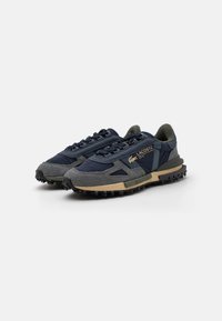 Sneaker blu navy con dettagli in suede grigio, suola in gomma textured, design con lacci e particolare di marca sul lato.