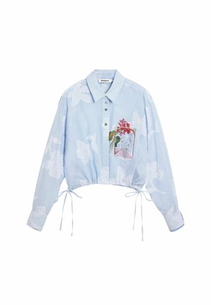 Camicia azzurra chiaro corta con bottoni, decorata con un motivo floreale bianco, bottoni multicolori e una piccola tasca con un disegno di fiore rosso.