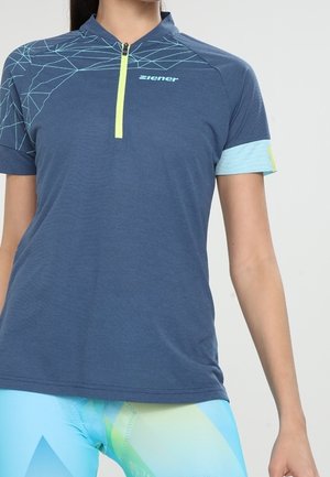 Kortärmad atletisk topp i marinblå med ett ljusblått mönster och dragkedja. Har en geometrisk design och kontrasterande ärmaccenter.