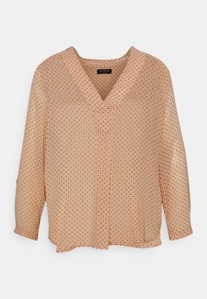 Blouse en voile rose avec des pois noirs, décolleté en V, manches longues et coupe décontractée. Texture douce avec un ourlet légèrement arrondi.