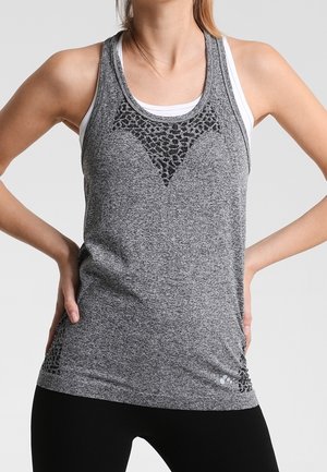 Donna che indossa un top sportivo grigio senza maniche con dettagli neri a stampa leopardata e leggings neri, in piedi con le mani sui fianchi.