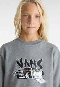 Grå sweatshirts med en färgglad grafisk design av en bil och ramp, med tydlig "VANS"-text och detaljerade accenter i svart och neontoner.