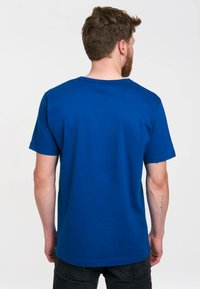 Modrá bavlněná tričko s kulatým výstřihem, krátkými rukávy a hladkou texturou. Bez viditelných log nebo vzorů; jednoduchý a neformální design.