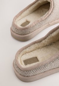 Svetlo hnedé, textúrované papuče s jemnou krémovou podšívkou. Majú prešité okraje a obdĺžnikovú značku s vyrazeným nápisom "NEXT".