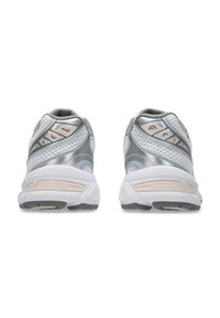 Chaussures de sport grises et blanches avec une tige en mesh respirant, un col rembourré et une semelle texturée avec des accents proéminents et des détails de rembourrage.