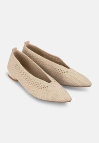 Bailarinas beige de tejido con punta fina y tacón pequeño. Presentan un diseño transpirable con detalles de corte y superficie texturizada.