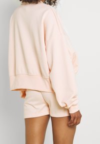Ljusrosa oversized sweatshirt med ribbat nederkant och ärmslut, ihop med matchande shorts. Mjukt, slätt tyg med en avslappnad passform.