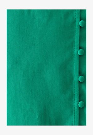 Roheline kangas siledat tekstuuriga, mille paremal serval on rida ringikujulisi nuppe. Kangas näitab kerget diagonaalset kootud mustrit.