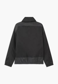 Czarna kurtka z kołnierzykiem, wykonana z gładkiego, lekkiego materiału. Posiada elastyczne mankiety i lekko ściągnięty pas.