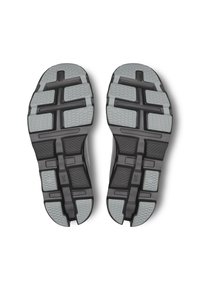 Semelles de baskets noires et grises avec un motif texturé. Les caractéristiques comprennent de profondes rainures, des accents hexagonaux et un matériau en caoutchouc durable.
