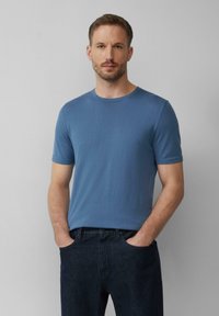 Niebieska koszulka typu crew-neck wykonana z lekkiego materiału, z krótkimi rękawami i gładką teksturą, w połączeniu z ciemnoniebieskimi dżinsami.