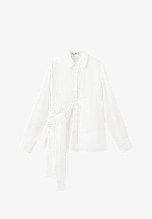 Bijela košulja s dugim rukavima na kopčanje, šiljastim ovratnikom i asimetričnim detaljem od tkanine u obliku kravate na lijevoj strani.