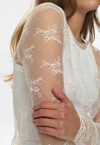 Kanten top met lange mouwen van doorzichtig materiaal, met bloemmotieven in off-white, een gestructureerde afwerking en een aansluitende lichaam met ronde hals.