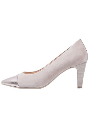 Beige Wildlederschuhe mit spitzem Schuhkopf und metallisch silberner Kappe. Der Absatz ist etwa 7,5 cm hoch und besitzt eine strukturierte, hellfarbige Sohle.