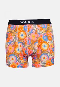 Boxer shorts colorés avec une base orange, arborant un motif floral en rose, bleu et crème, et une ceinture élastique noire étiquetée « WAXX ». 