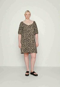 Vestido de padrão de leopardo em castanho claro com mangas curtas em balão e decote em V. Combinado com sandálias rasteiras pretas. Tecido suave e macio.