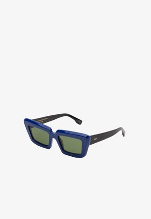 Occhiali da sole blu a forma quadrata con lenti verdi, caratterizzati da una montatura in plastica audace e braccia nere. Dettaglio del logo dorato sulla tempia.