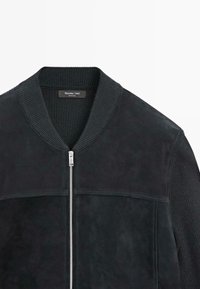 Giubbotto bomber in suede nero con colletto e polsini in maglia, chiusura a zip e cuciture tonali. Texture liscia con un design moderno e strutturato.