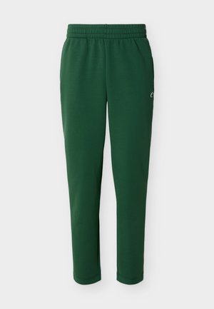 Temno zelene tekaške hlače z elastičnim pasom, stranskimi žepi in majhnim belim logotipom na zgornjem delu stegna.