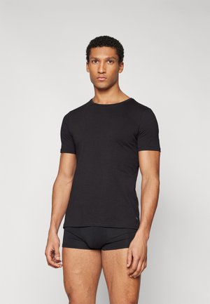 Schwarzes T-Shirt mit kurzen Ärmeln aus weichem Stoff. Verfügt über einen klassischen Rundhalsausschnitt und eine schlanke Passform. Getragen mit schwarzen Boxer-Shorts.
