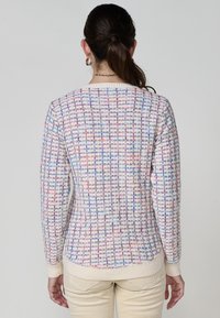 Pull en tricot avec un motif tissé multicolore, doté d'un col rond, de poignets et d'un ourlet côtelés, avec des teintes pastel et une finition texturée.