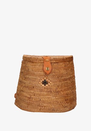 Cesto rotondo in paglia intrecciata con una tracolla in pelle beige e chiusura a bottone. Presenta un motivo a croce in filo nero sul davanti.