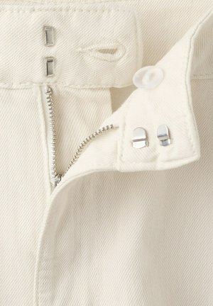 Ceinture de pantalon en denim blanc avec fermeture éclair argentée partiellement ouverte et doubles fermoirs métalliques à crochet et barre sur la languette de fermeture.
